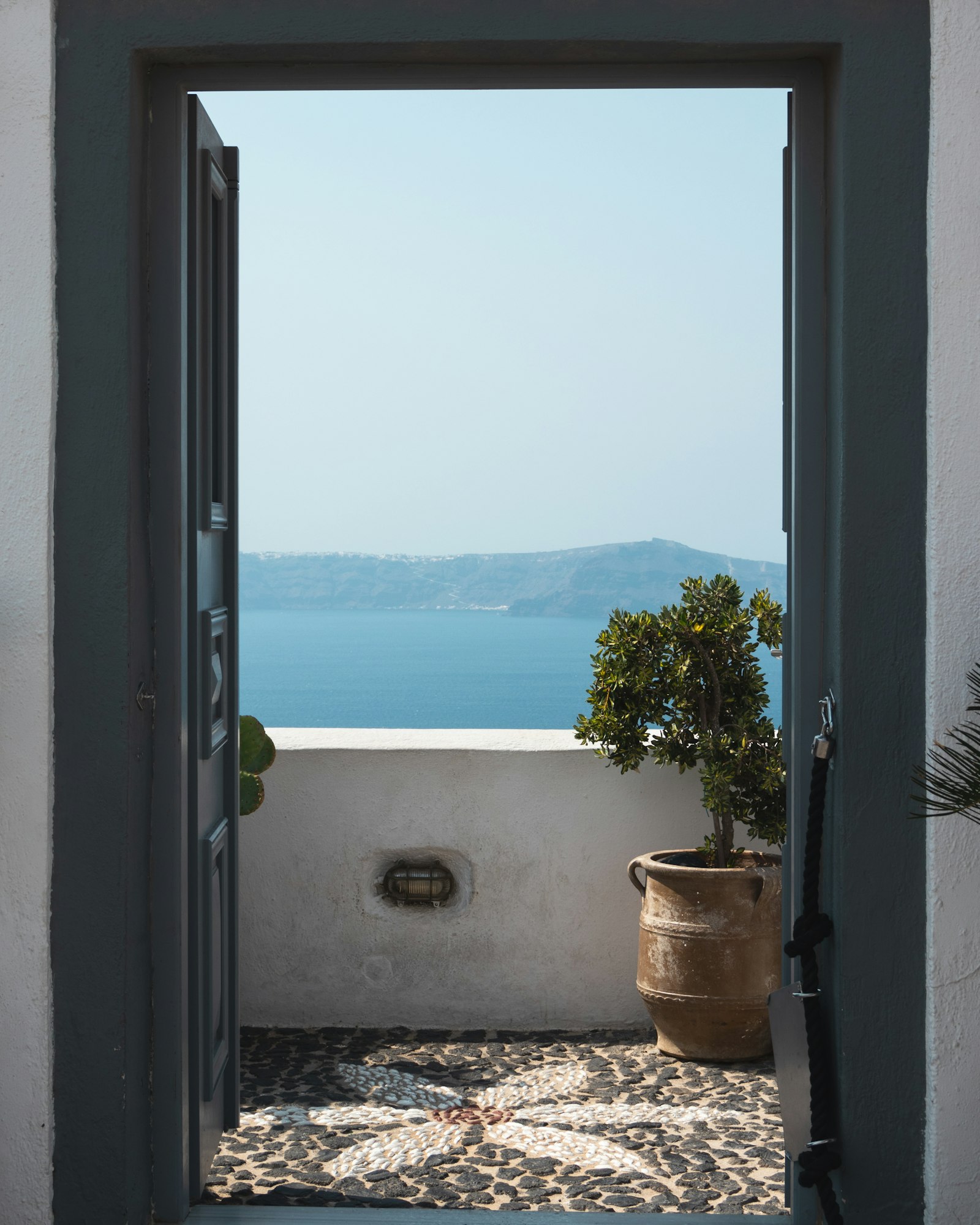 An open door from a whitewashed room onto a terrace above the sea
